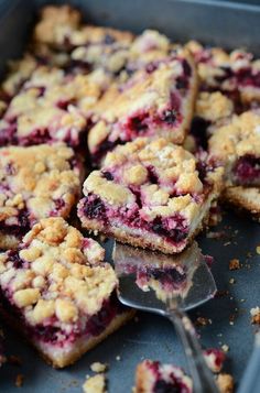 blueberry crumb bars are cut into squares and placed on a baking sheet with a spoon