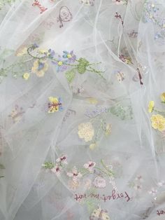 the fabric has flowers on it and is white with pink, yellow and green accents