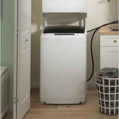 a white washing machine sitting next to a laundry basket on top of a wooden floor