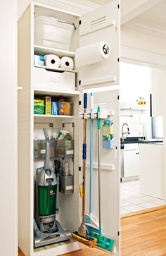 the inside of a white cabinet with cleaning supplies in it and two mop's