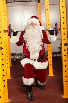 a santa clause is doing squats with a barbell in front of his face