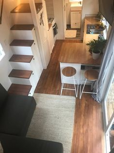 a small living room with stairs leading up to the top floor and kitchen in the background