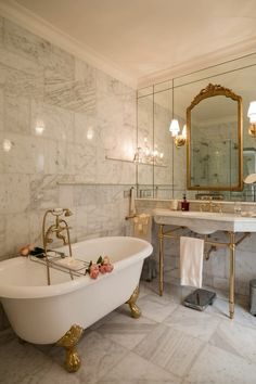 a white bath tub sitting under a bathroom mirror