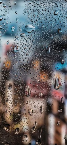 raindrops on the window with buildings in the back ground and people walking by