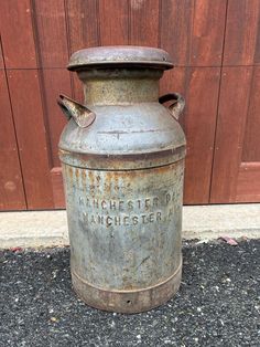 an old metal container sitting in front of a wooden wall with the word winchester on it