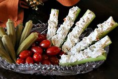 a glass bowl filled with cucumbers, tomatoes and celery sticks on top of a table