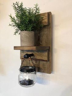 a potted plant is hanging on the wall next to a mason jar filled with water