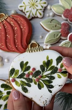 a hand holding an ornament decorated with holly and berries