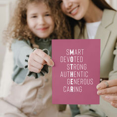 a mother and daughter holding up a card that says smart devoted strong authentic generous caring