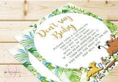 the lion king baby shower card is displayed on a wooden surface with greenery around it