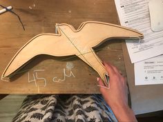 a person working on a wooden bird with numbers and measurements attached to the wood frame