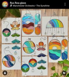 six different stained glass sun catchers hanging on a wooden table next to a potted plant