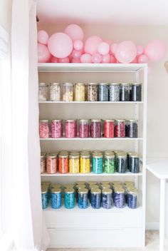 a shelf filled with lots of different types of confetti and balloons on top of it