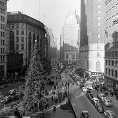 an old black and white photo of a christmas tree in the middle of a city