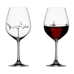 two wine glasses filled with red wine and a shark