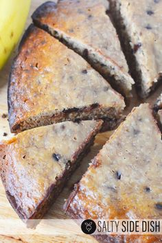 a sliced cake sitting on top of a wooden cutting board next to a yellow banana