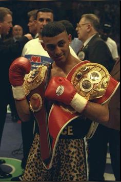 a man holding two boxing gloves in front of his face and other people standing behind him