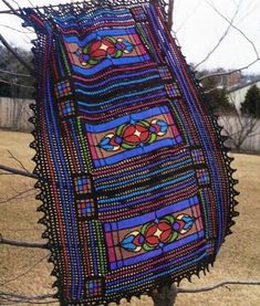 a colorful crocheted blanket hanging from a tree