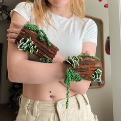 a woman is holding two knitted gloves with trees on them and grass growing out of them