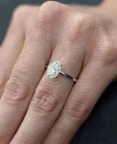 a woman's hand with a diamond ring on her left hand and the other hand holding an engagement ring