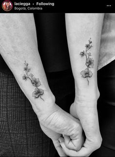 two people holding hands with small tattoos on their wrist and the other one has a flower