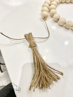 a tasseled beaded necklace and wooden beads on a white counter top,