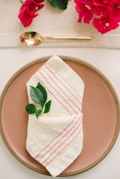 a pink plate topped with a napkin and flowers