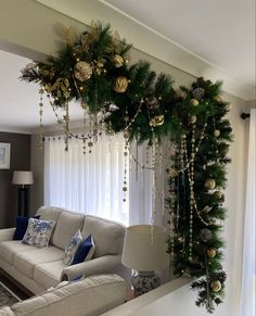 a living room decorated for christmas with garland and ornaments hanging from the ceiling over the couch