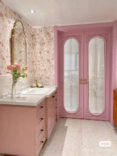 a pink bathroom with double doors and flowers on the wall next to the sink area