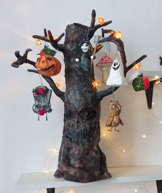 a tree with halloween decorations hanging from it's branches and lights on the branches