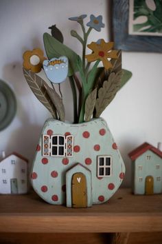 a vase with some flowers in it sitting on a table next to other small houses