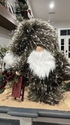 a large stuffed animal sitting on top of a wooden table next to christmas decorations and greenery