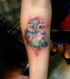 an owl tattoo on the leg with watercolor paint splatters all over it