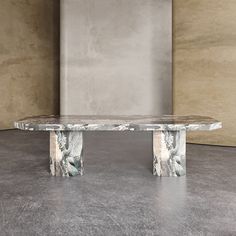 a marbled bench sits in front of a concrete wall and cement flooring area