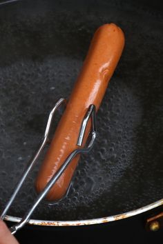 a hot dog being cooked in a frying pan