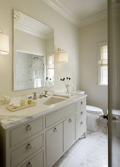 a white bathroom with two sinks and a toilet in the corner next to a large mirror