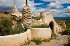 a house made out of clay with holes in the roof and walls, on top of a hill