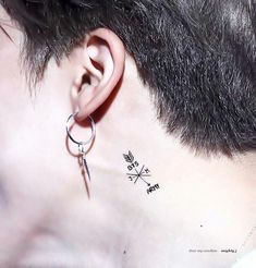 a man's ear with an arrow tattoo on it