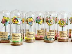 there are many glass vases with flowers in them and labels on the bottles for each one