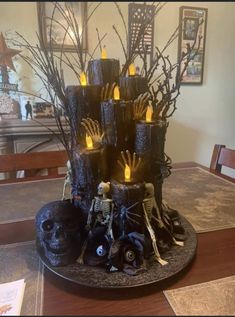 a table with candles and decorations on it in the shape of a skull, tree branches, and skeleton hands