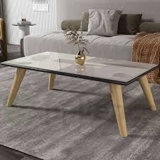 a glass coffee table with wooden legs in a living room