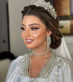 a woman wearing a tiara and dress with pearls on her head is smiling at the camera