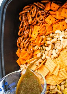 a bowl filled with different types of snacks and dip in the middle, next to a glass container full of nuts