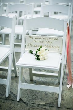 two white chairs sitting next to each other with flowers on the seat and a sign that says, we know you would be here today