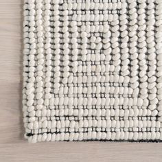 a white and black rug on top of a wooden floor