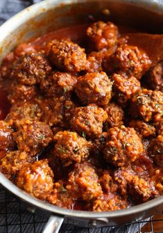 meatballs and sauce in a pan with a wooden spoon