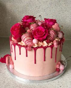 a cake with pink icing and flowers on top is sitting on a countertop