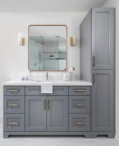 a bathroom with gray cabinets and a large mirror