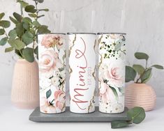 three personalized tumbles with floral designs on them and greenery in the background