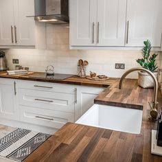 a kitchen with white cabinets and wood counter tops, an island sink and dishwasher